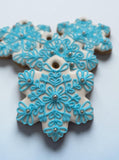 Weiße Schneeflocken aus Lebkuchen, verziert mit blauer Zuckerglasur und silbernen Zuckerperlen. Kann an den Weihnachtsbaum gehängt werden. Die Schneeflocken sind freihändig verziert, jedes Stück ist ein bisschen anders.